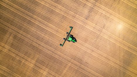 Vue aérienne d'un tracteur travaillant un champ, illustrant l'optimisation des transports agricoles.