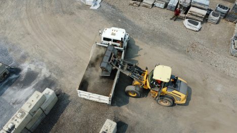 Engin de chantier chargeant des matériaux dans un camion sur un site de gestion des transports.